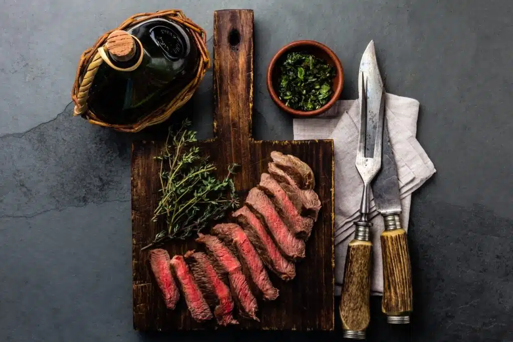 a steak on a cutting board with a knife and fork