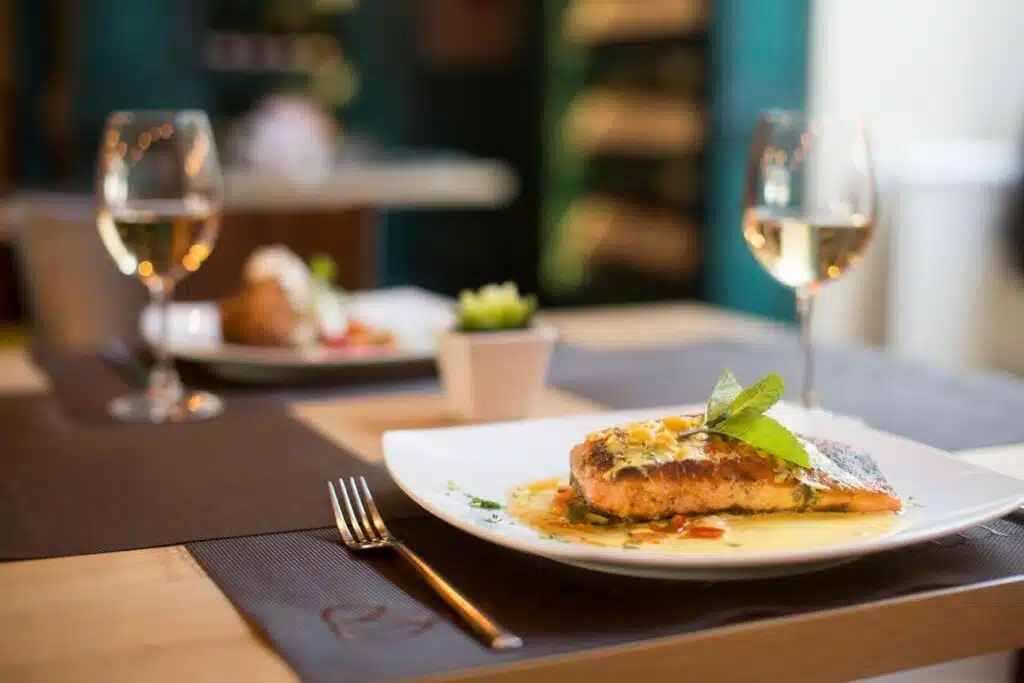A plate of fish with a glass of wine on a table.