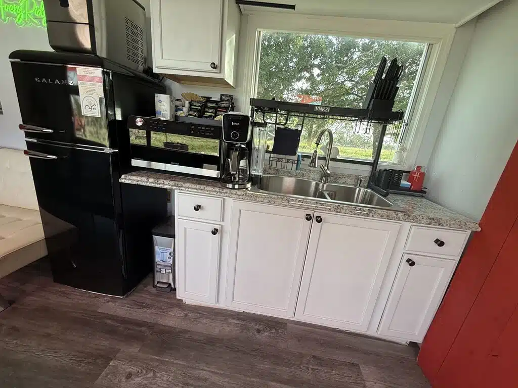 A small kitchen with a black refrigerator, sink, and coffee maker